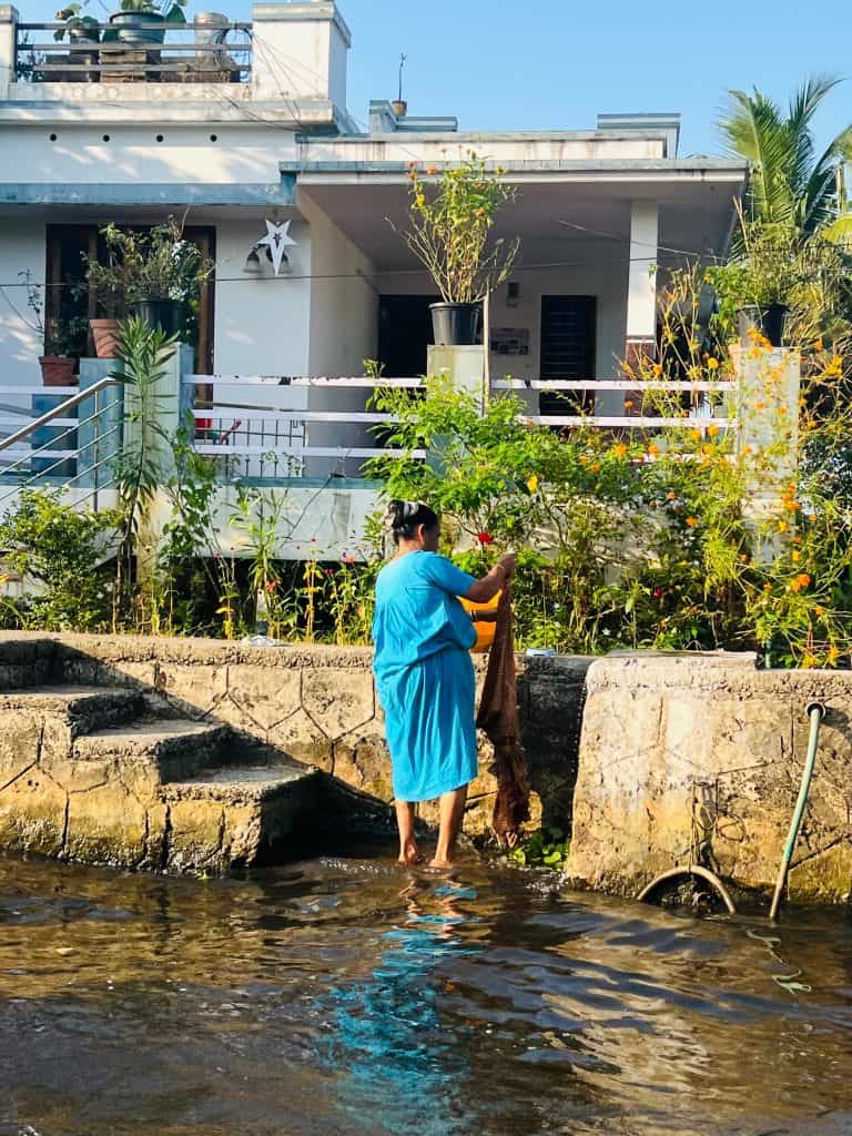 Lady washing her clothes on the bank of the backwaters in Kerala