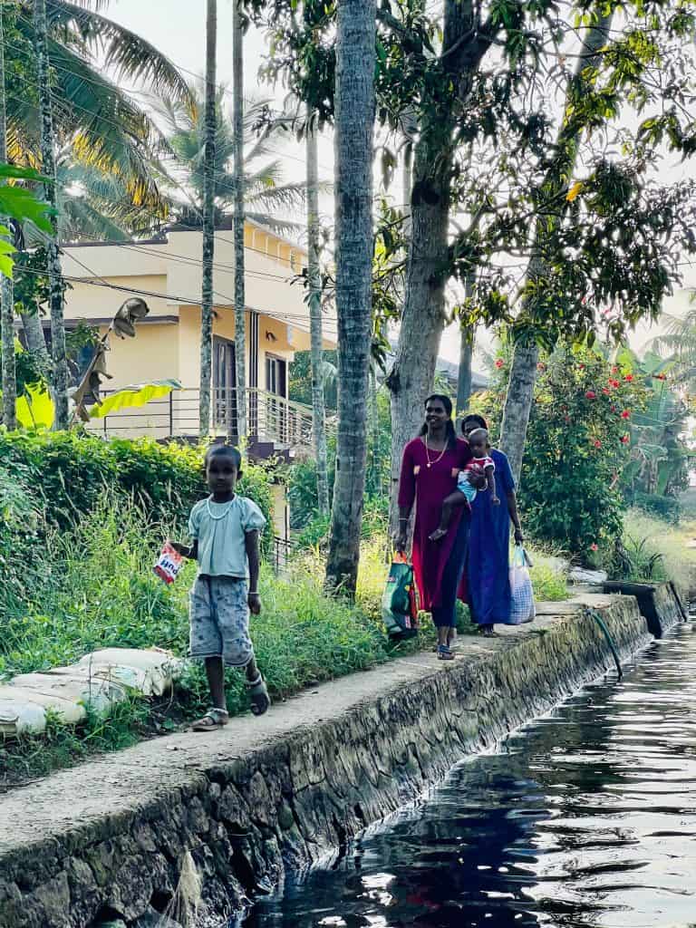 2 women and their children walking down the banks of the Kerala backwaters