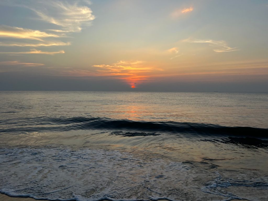 Sunset on Marari Beach with calm waves. Bright red and ornage sun filling the sky