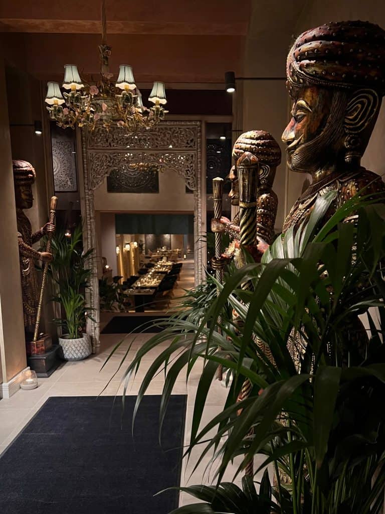 The Rajasthani bronze statued men in the entrance, shaded with a plant at Varanasi, Leicester