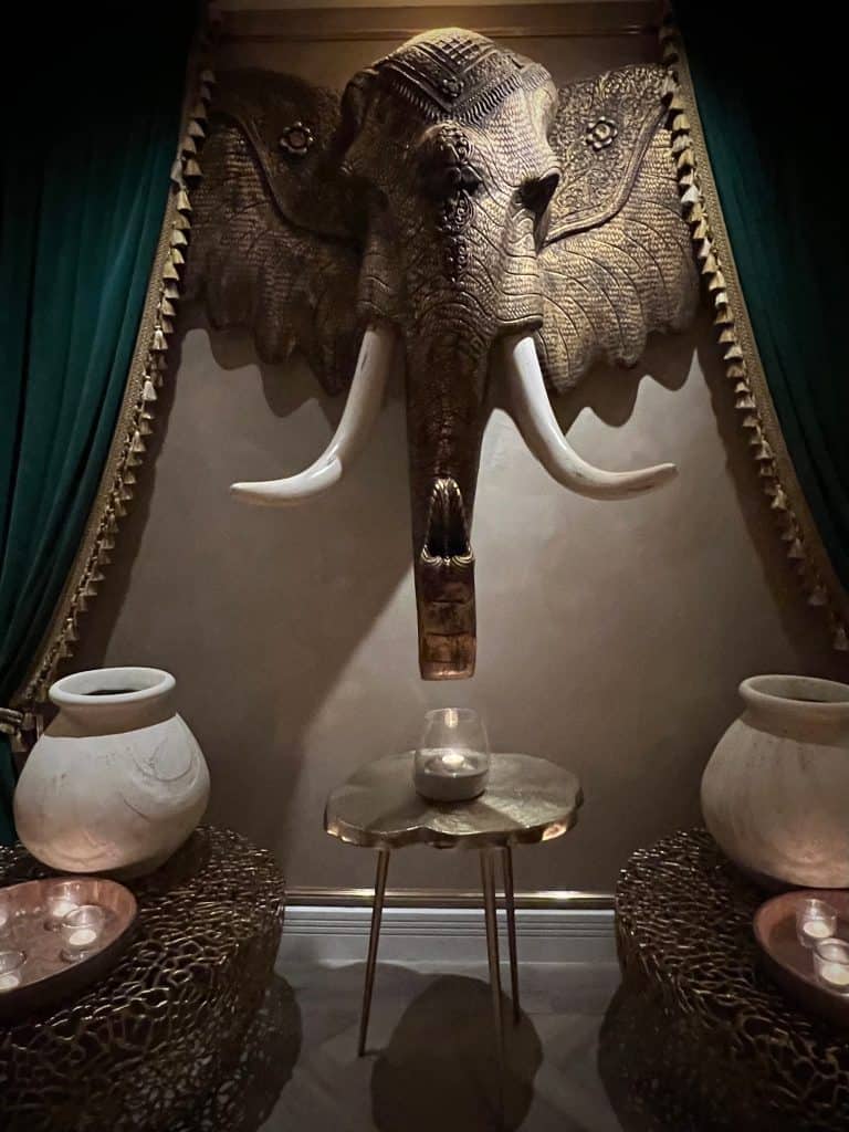 The elephant head made of bronze with white pots and velvet teal draping around the sides at Varanasi, Leicester