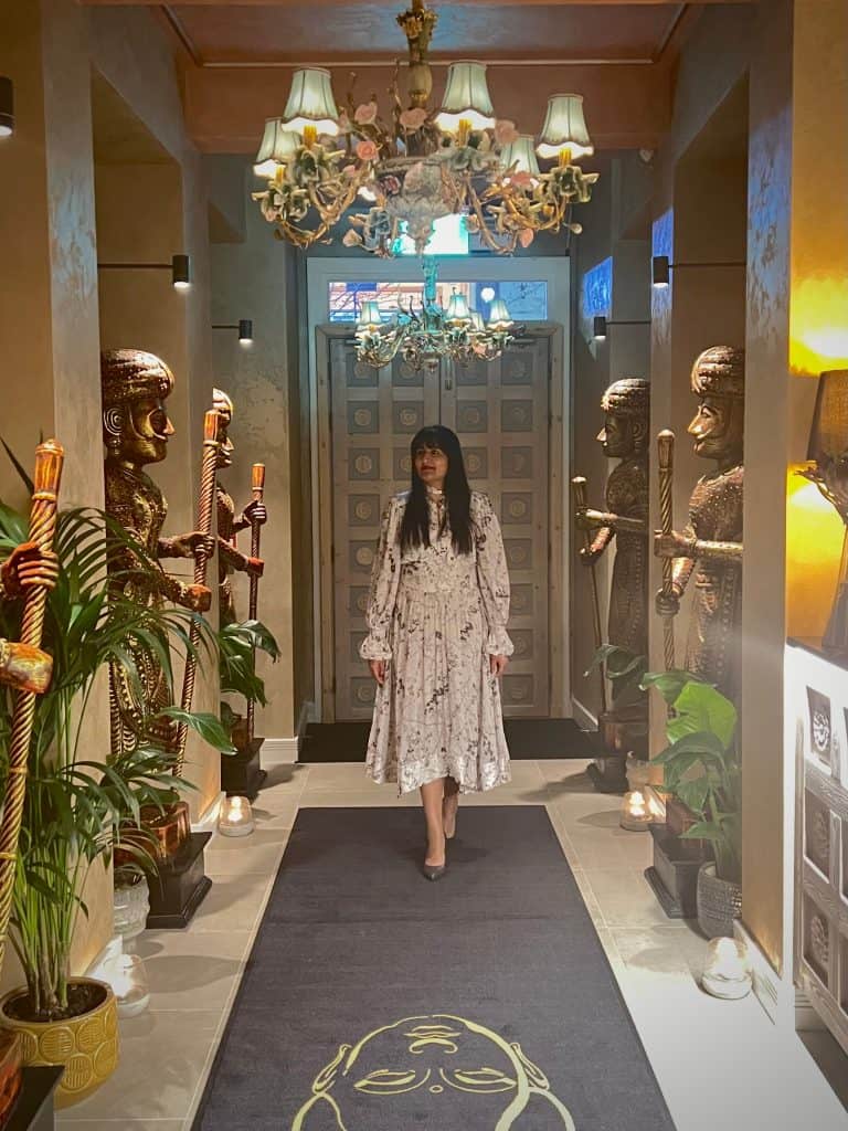 Bejal walking down the entrance aisle in a floaty white dress and grey croc patterned heels.