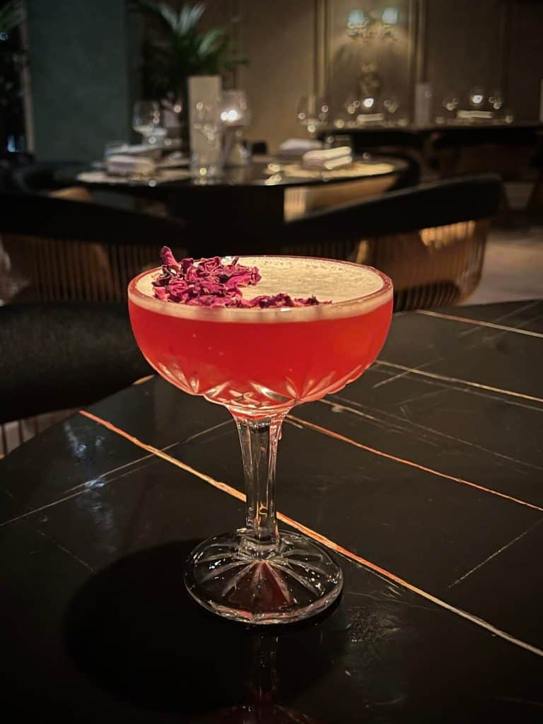 Res rose petal Martini on a black table at Varanasi, Leicester