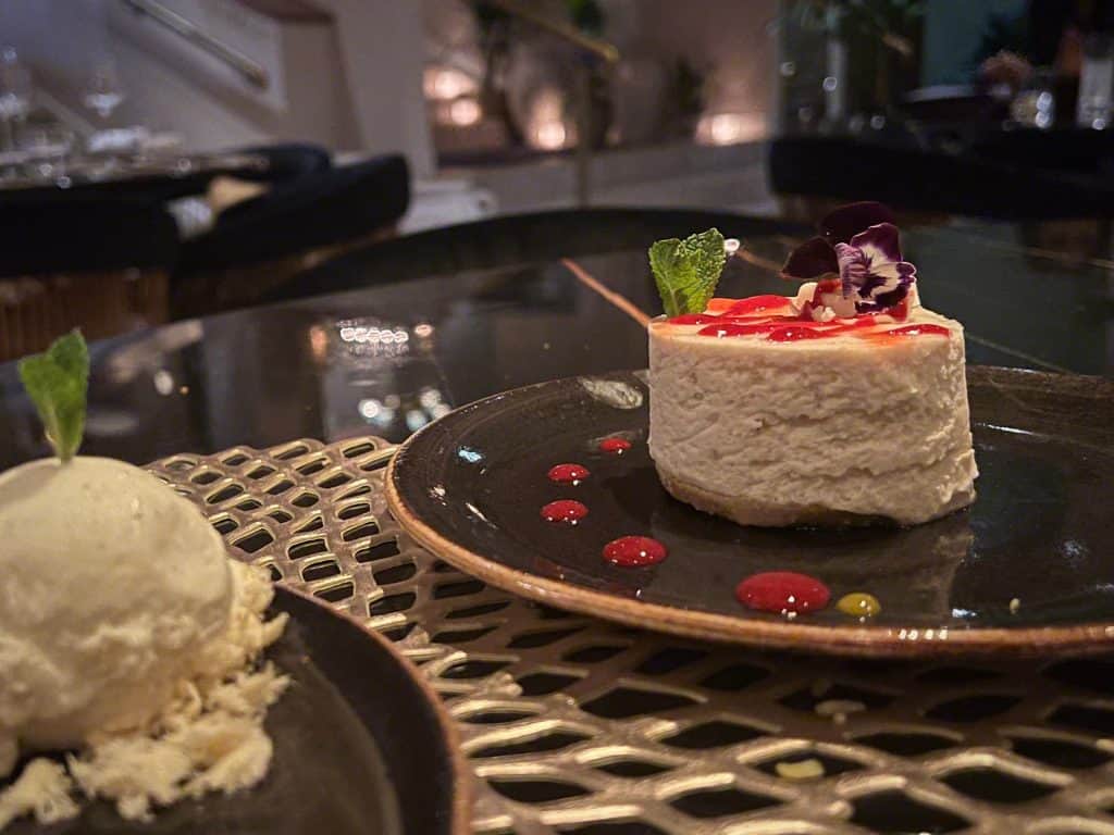 Indian Fine Dining At Varanasi: Summer fruit cheesecake topped with fruit on a black plate at Varanasi, Leicester