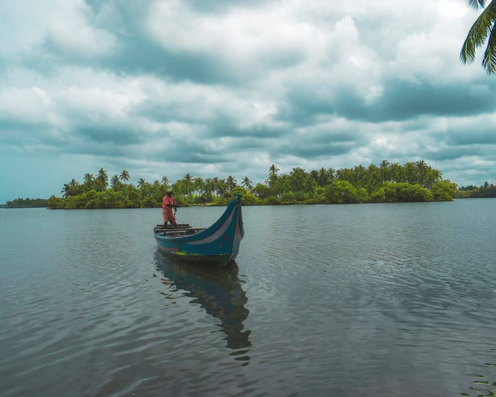 Canoe sailing down the Kerala backwaters with palm trees in the background