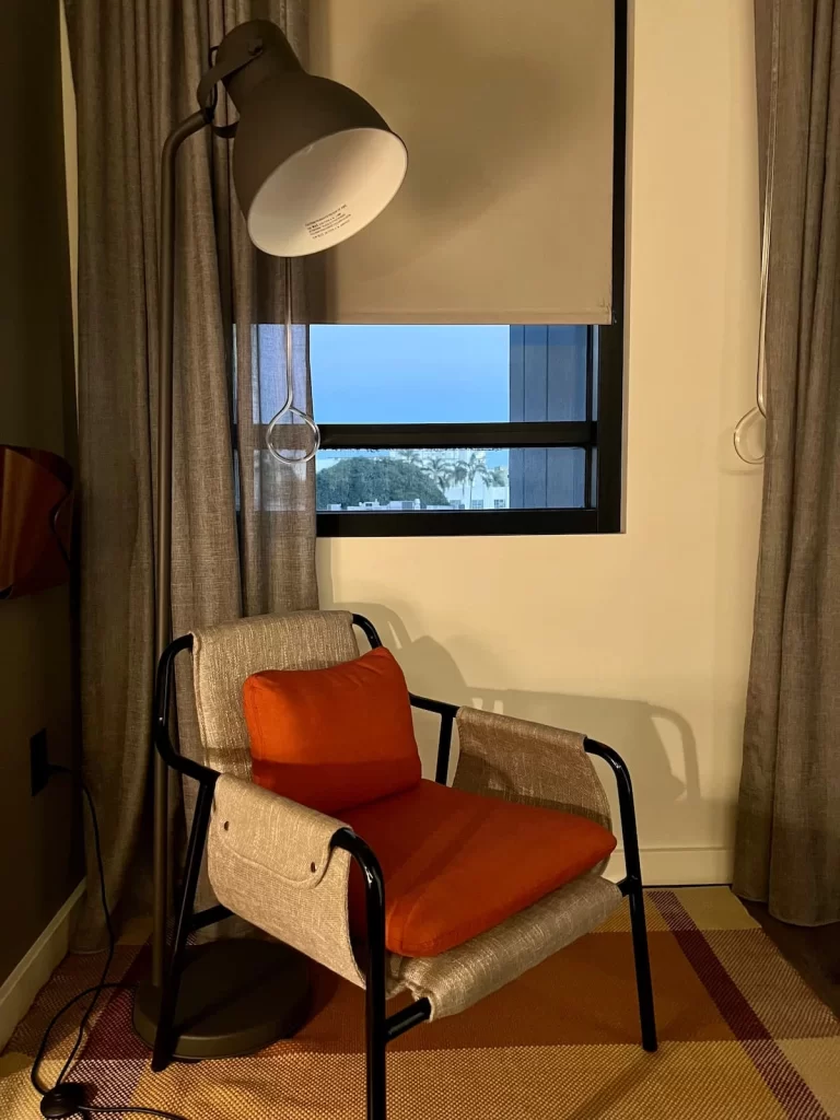 Beige armchair with orange cushion in the Queen Room at Moxy San Diego