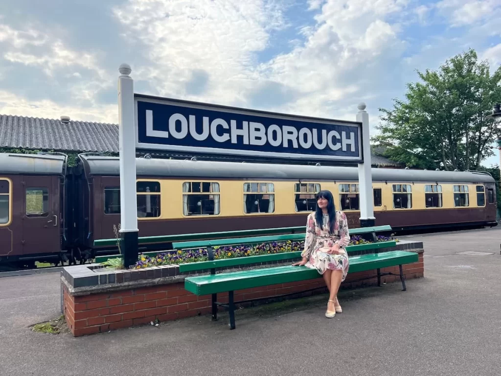 Bejal sat on bench at Loughborough Station with the Loughborough sign above