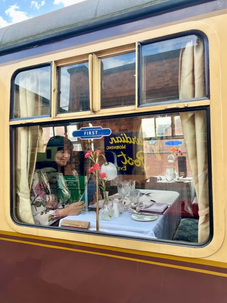 Bejal sat at window on carriage looking through the drinks menu on the Charnwood Forester train at Loughborough