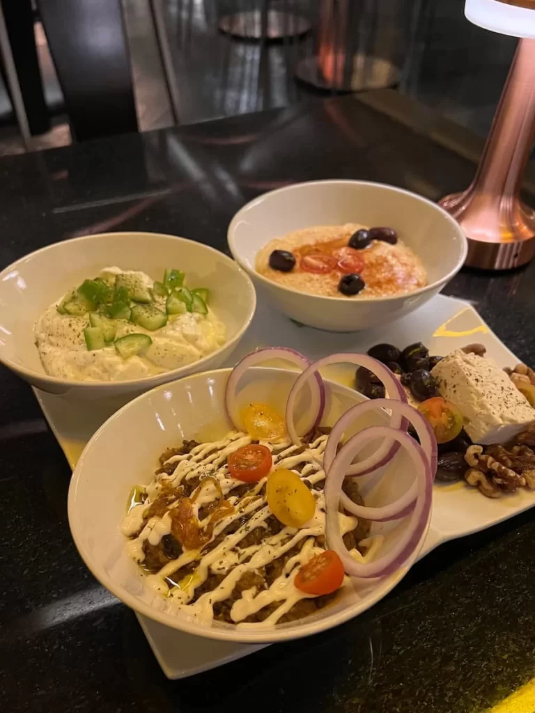 3 Meze plates containing, feta, hummus and a salad with flat bread at Bandar, San Diego