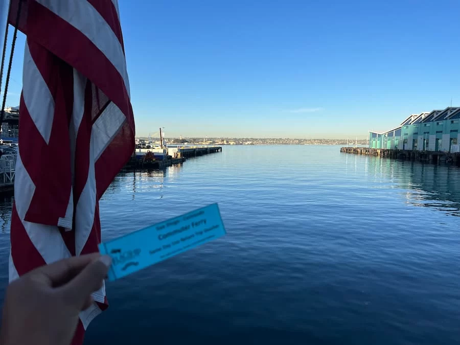 San Diego Ferry Pier with boats in the background and Bejal holding commuter ticket.