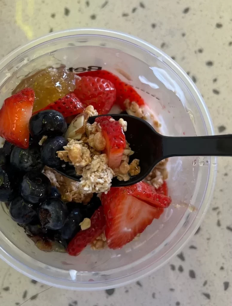 Yoghurt bowl with spoon containing blueberries, strawberries, granola and yoghurt at Better Buzz Coffee, Coronado