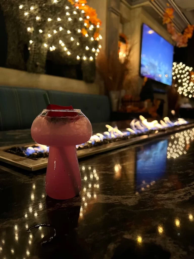 The Lavender Haze cocktail in front of the fire table at Rustic Root, San Diego