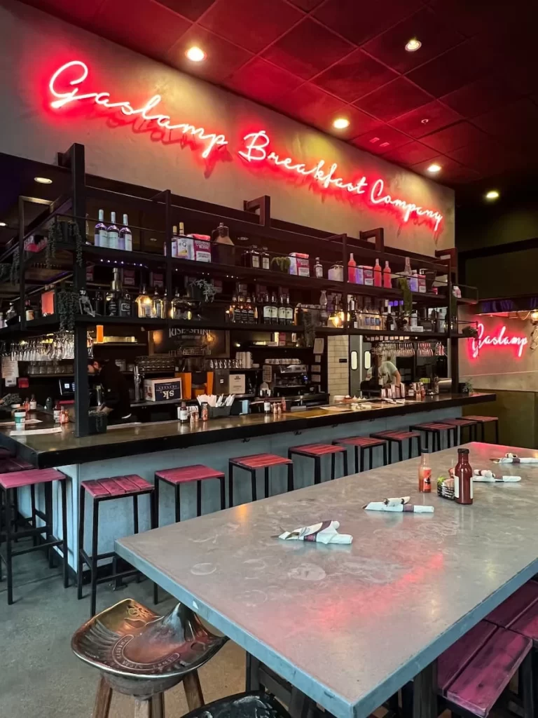 The bar area seating and neon pink sign of teh Gaslamp Breakfast Company, San Diego