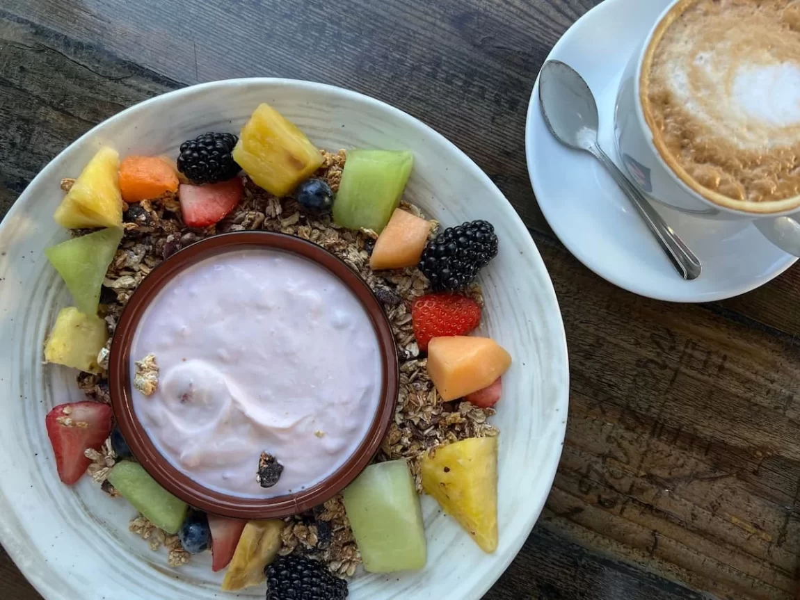farmer's Table cafe flat lay of granola, fruit and yoghurt bowl with a latte