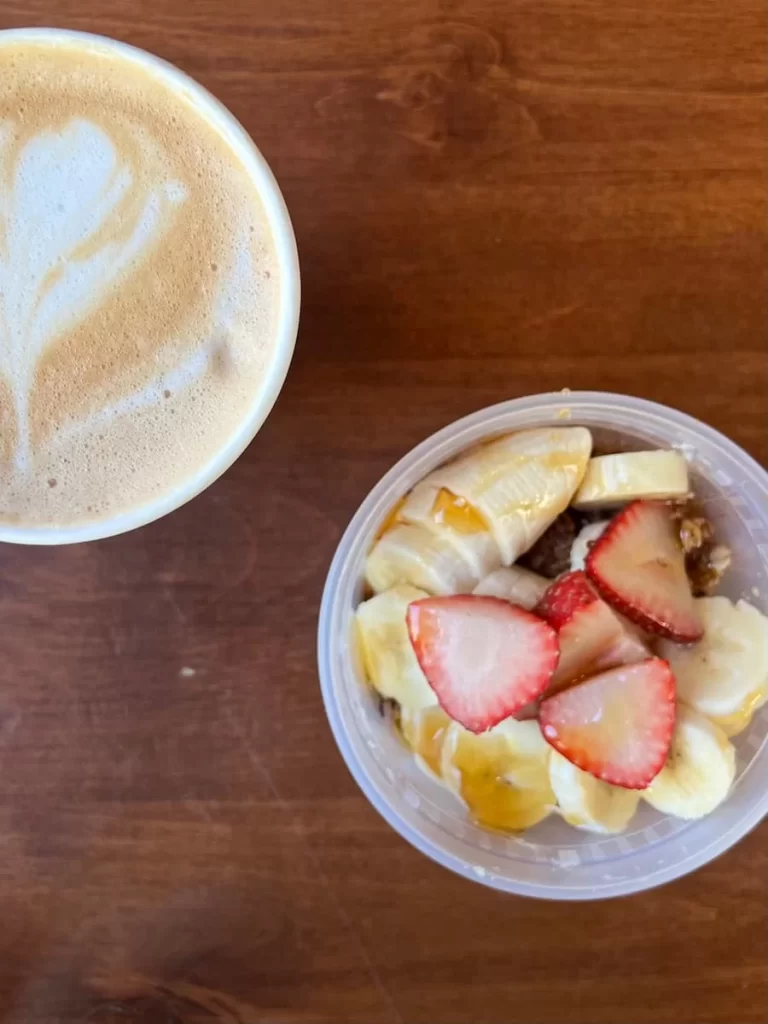 Top lay of the acai bowl with layered strawberries and bananas and coconut lattes at Lani Coffee, San Diego