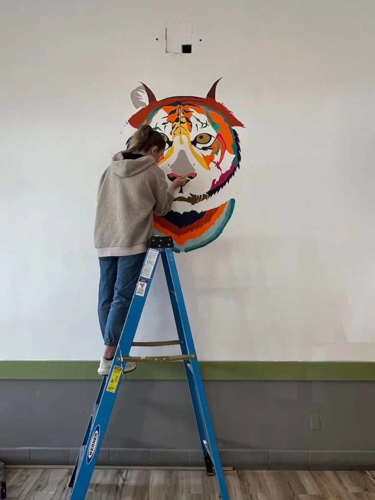 Coffee and Breakfast places in San Diego: Lady painting multicolour tiger mural in Tiger Cafe, San Diego