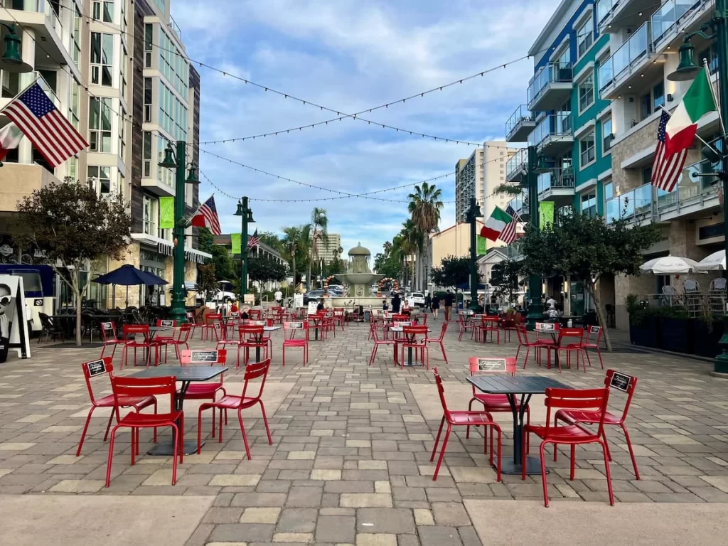 Piazza della Famiglia with red chairs and tables scattered around during the day in LIttle Italy, San Diego