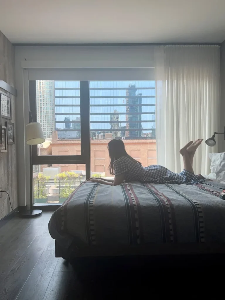 Bejal lying on bed with a city view in background at Moxy, Chicago
