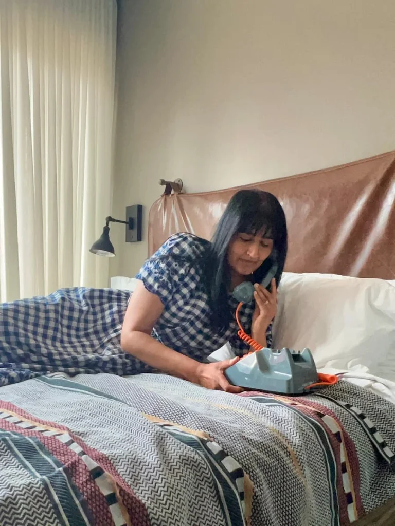 Bejal on the retro phone at Moxy Chicago wearing a blue and white checked dress