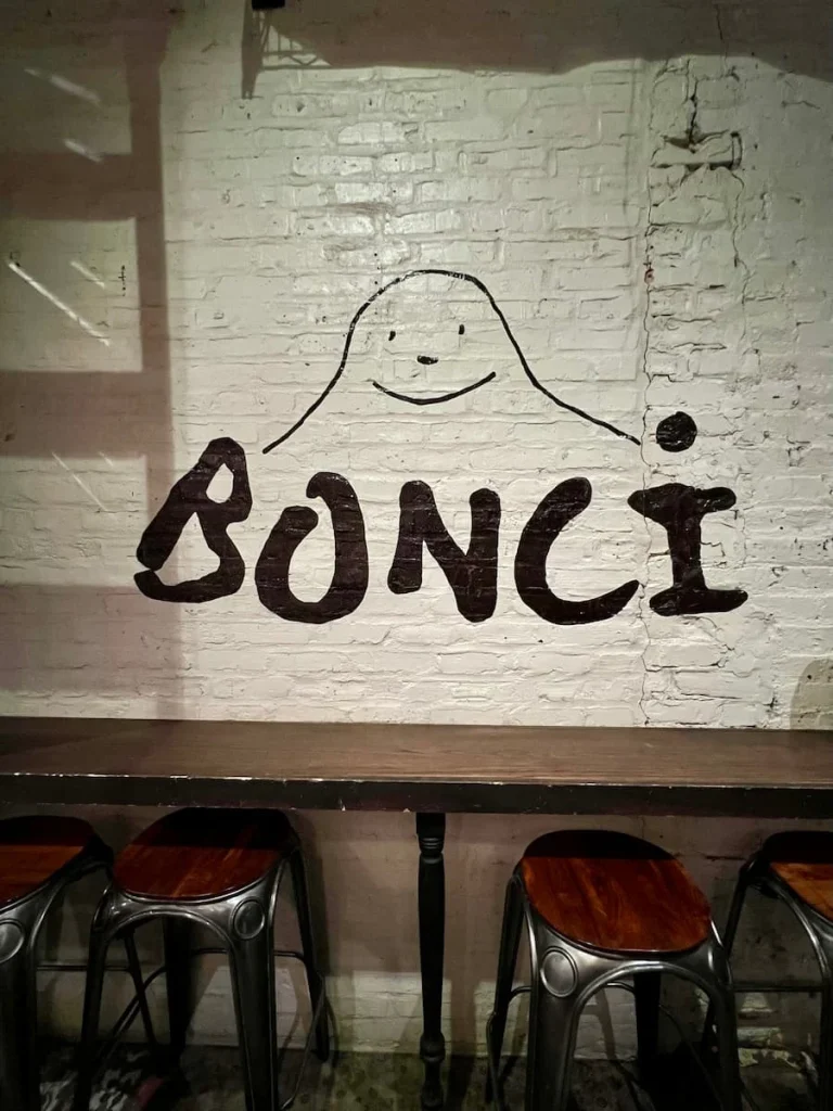 Bonci sign on the wall inside of the restaurant in West Loop, Chicago with brown stools underneath