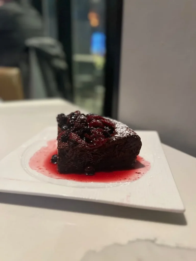 A slice of chocolate souffle topped with cherries and berries on a white plate at The Albert Restaurant, Hotel EMC2, one of the places with vegetarian friendly food in Chicago