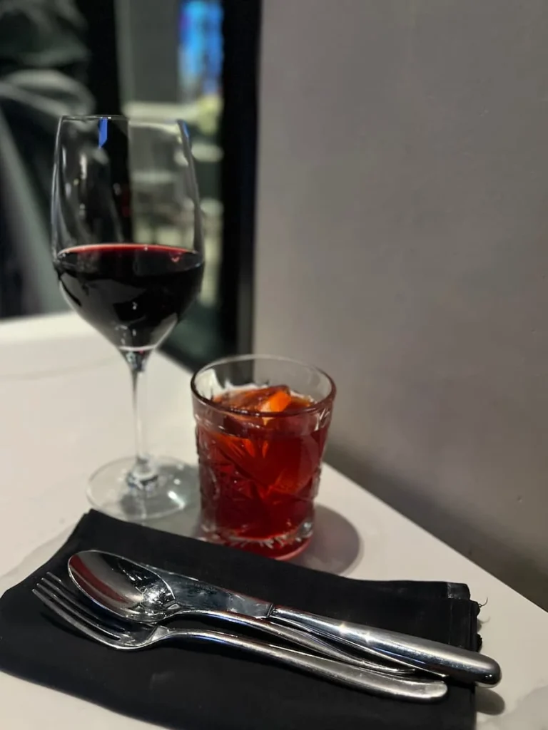 Strawberry Fields cocktail next to cutlery and glass of red wine at The Albert restaurant at Hotel EMC2, one of the places with vegetarian friendly food in Chicago