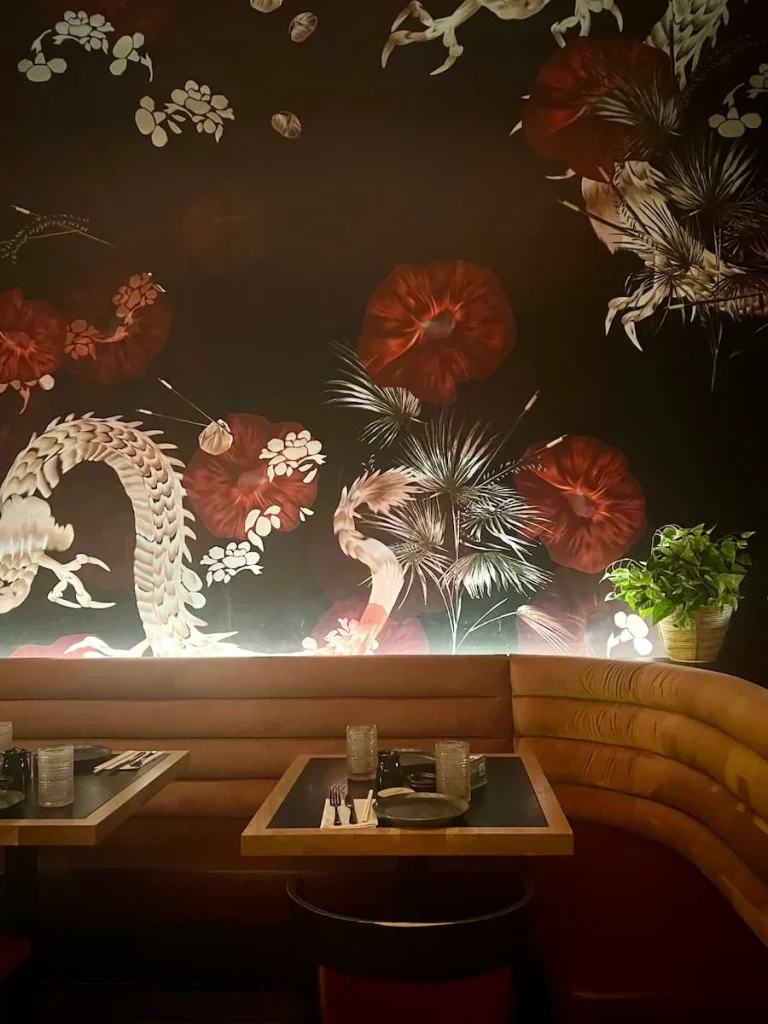 The wallpaper and seating area at PLANTA Queen Chicago with colourful designs and salmon coloured seat coverings, vegetarian friendly food in Chicago