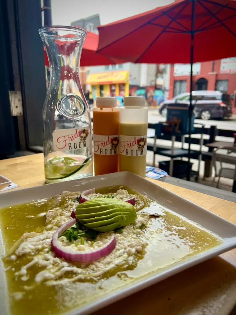 Enfrijoladas verdes con Huevos at Frida Room, Chicago with sauces in the background and a street view