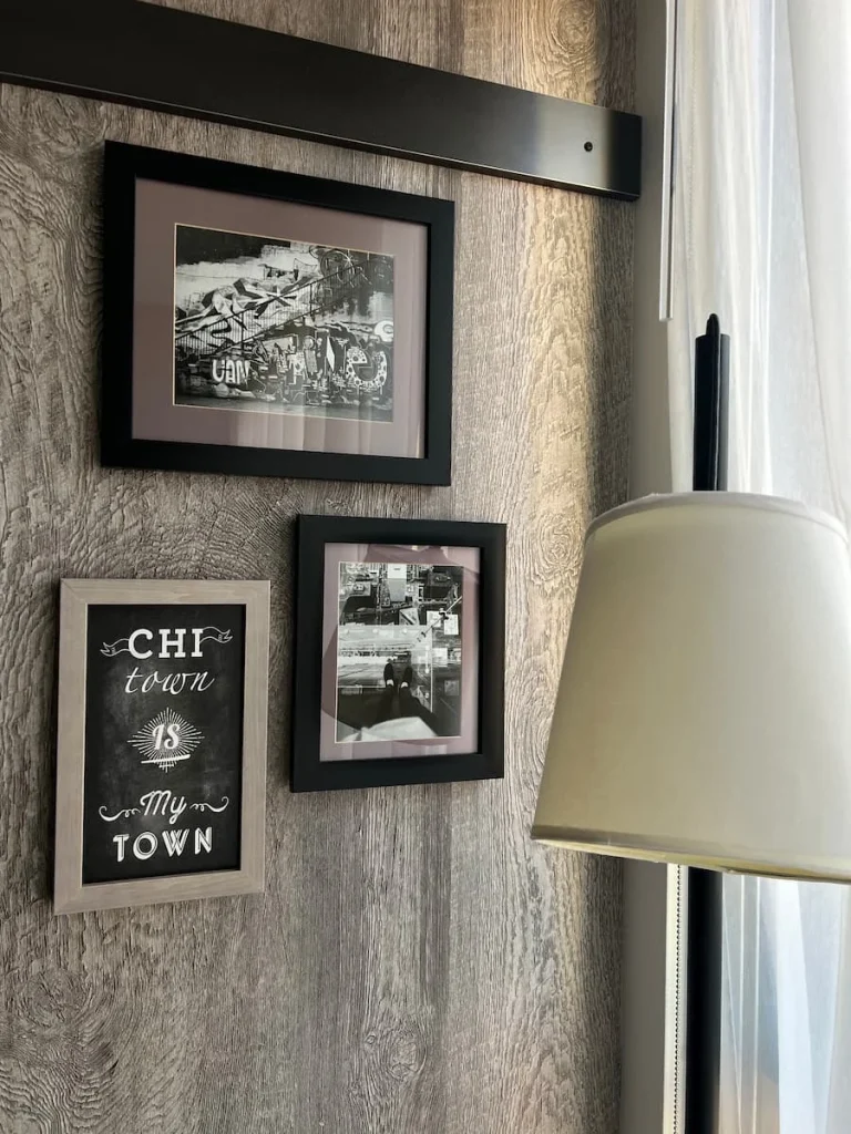 Framed photos of the city at Moxy, Chicago in a guest room with black frames and a white lamp shade next to it