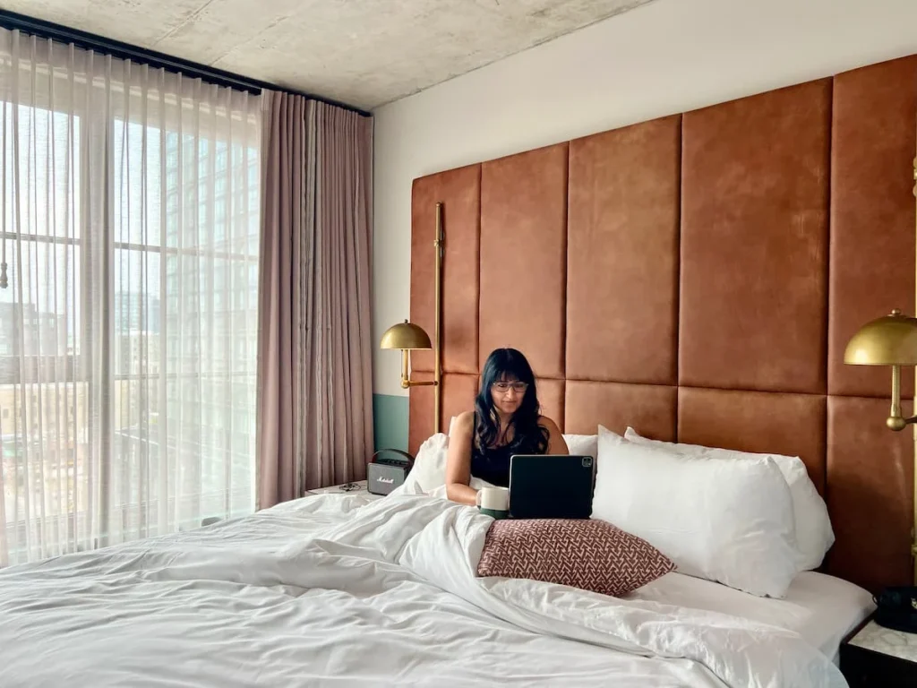 Bejal sat in bed with laptop at The Hoxton, Chicago