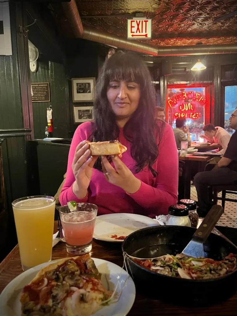 Bejal eating a slice of vegetarian Deep Dish pizza at Pizzeria Uno, Chicago