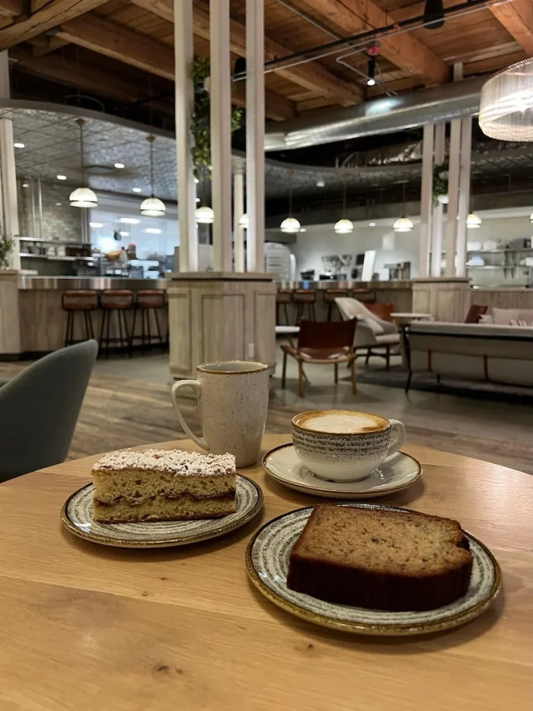 Coffees, banana bread, Bakewell cake at Good Ambler with beautiful cafe interiors in the background. One of the coffee shops in Chicago for vegetarians