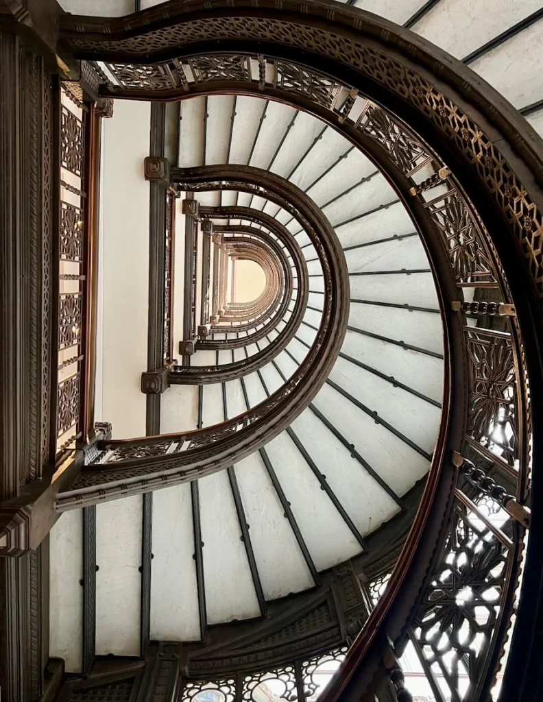 Oriel Staircase inside the Rookery Building, Chicago with the white stairs and dark brown bannister and intricate carvings, one of the non touristy things to do in Chicago