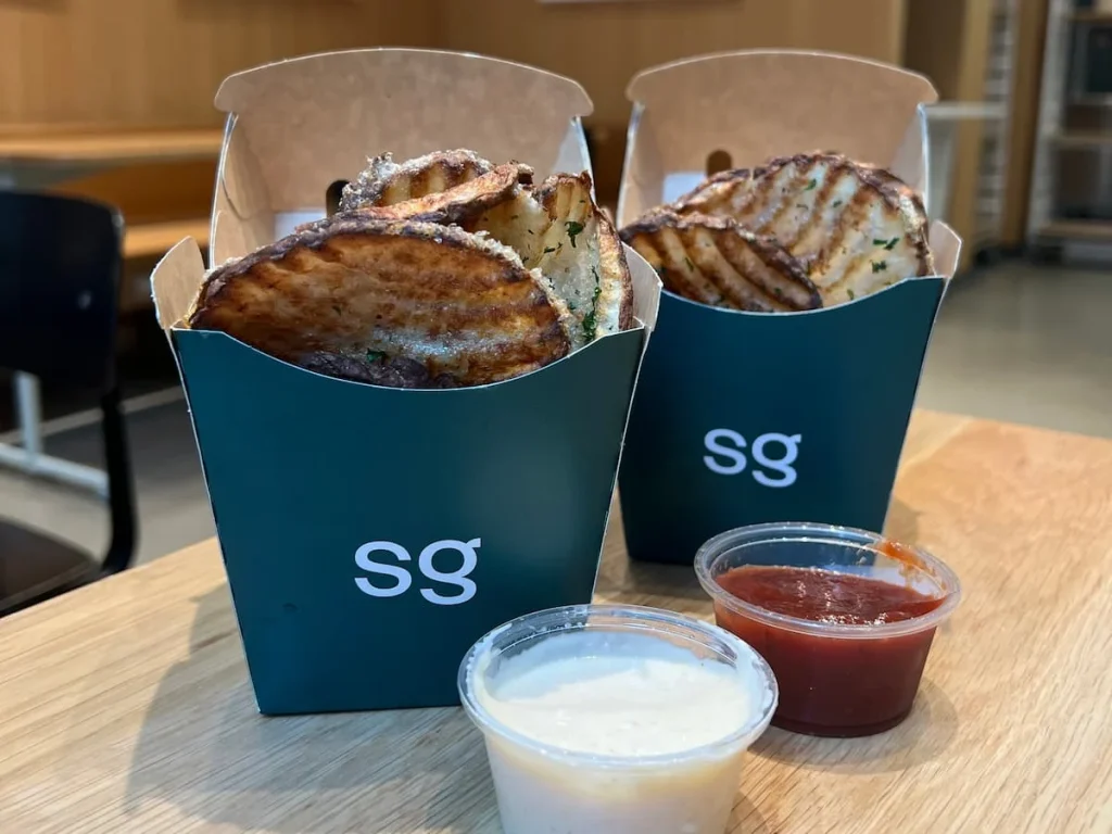 Potato ripple fries in green paper containers fried in avocado oil served with garlic mayo and Ketchup at SweetGreen, Streeterville Chicago