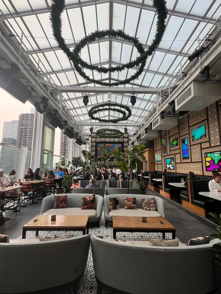 Roof on thewit Chicago interiors with floor to ceiling windows, sofas at the front, tables and booths at the side and the main bar at the end.