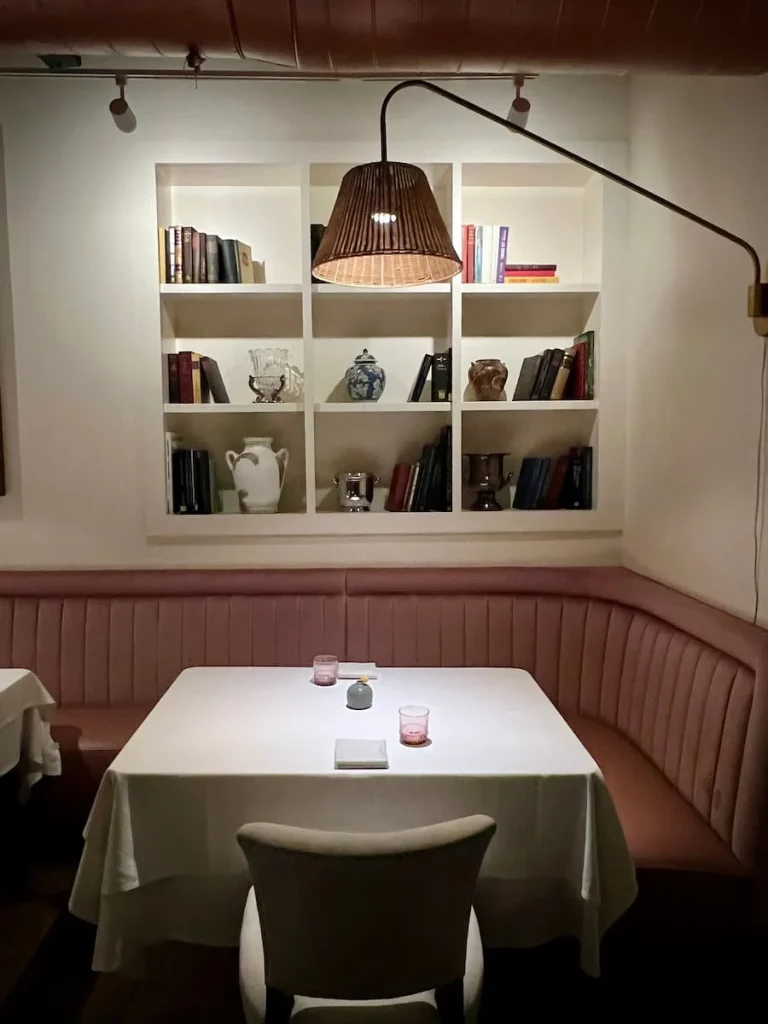 salmon pink Seating area with books and vases on the shelf above at Indienne, Chicago