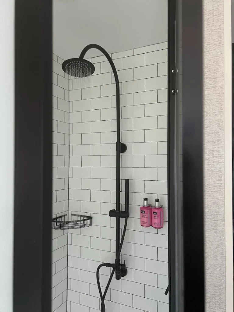 Hairdryer, steamer and bag at Moxy, Chicago featiring black rainfall shower and MUK pink bottle toileteries
