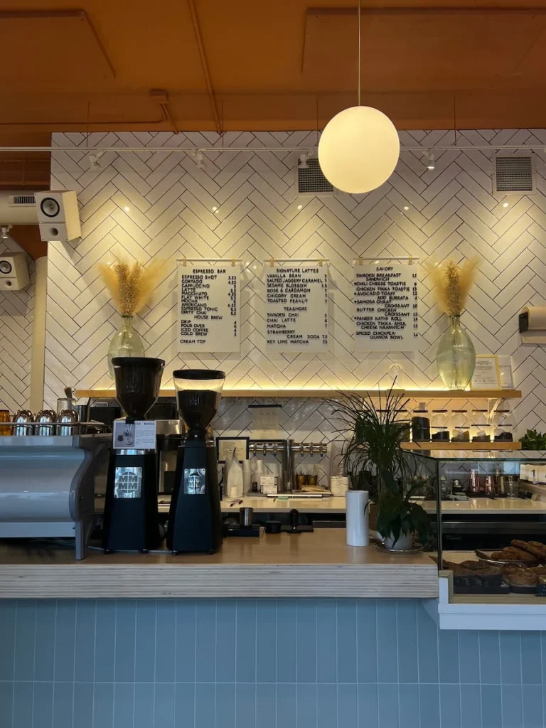 Swadesi Cafe counter with menu and coffee machine in Chicago. Bright white and duck egg blue decor