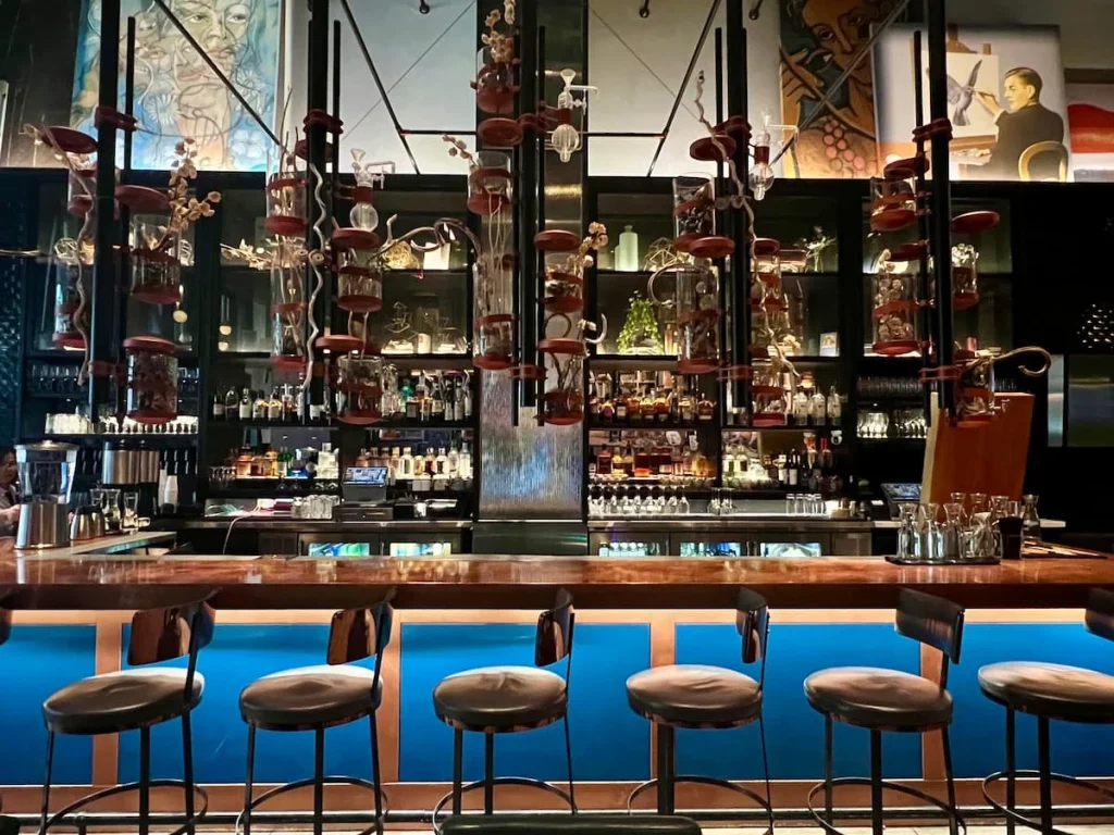 The feature bar, lined with drinks with gold decorative accents at The Albert Restaurant, Hotel EMC2, one of the places that serves vegetarian friendly food in Chicago