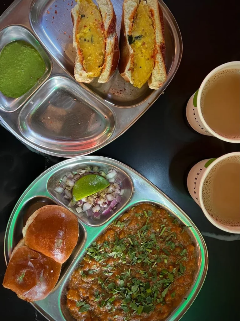 Vada pau and Pav bhaji (bread rolls, bhaji curry with onion and lime) top lay with 2 cups of masala chai at Mazala Pizza by Moti cafe, Chicago. One places that serves vegetarian friendly food in Chicago