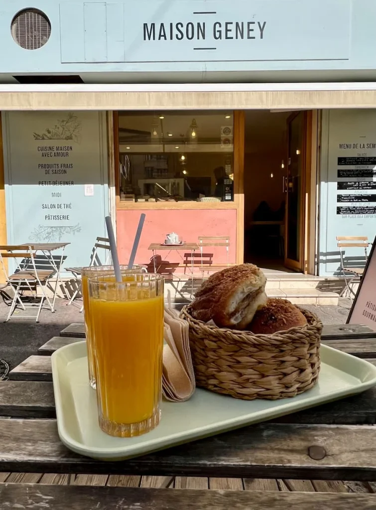 Orange juice and breakfast pastries at Maison Geney, Marseille on the terrace with the cafe n the background