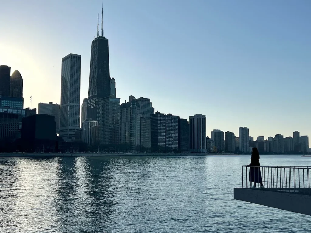 Bejal's silhouette standing on balconty area looking at the Streeterville skyline at Milton Lee Olive Park, Chicago. The photo is taken following sunset, when it's getting dark