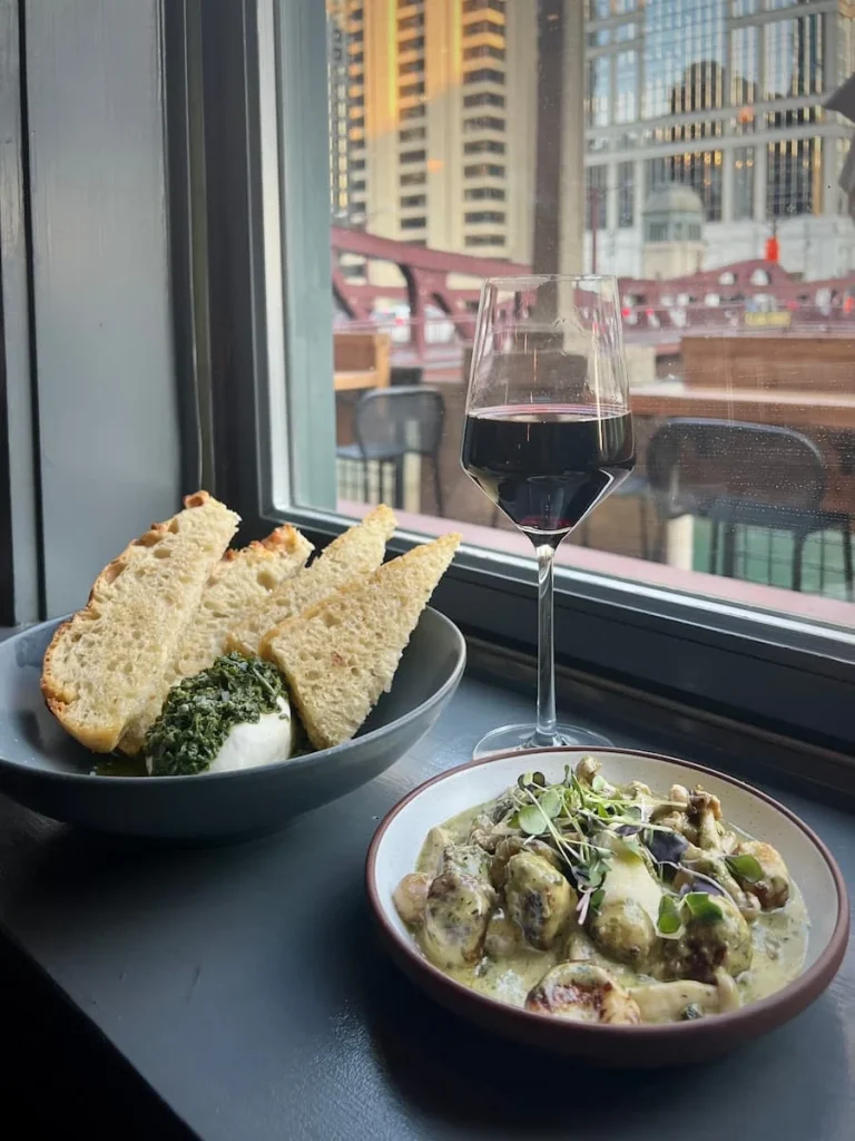 Burrata with sour dough bread and Gnocchetti at American Kitchen, Chicago. The image is framed with the window and a veiw of the Chigcao River and Well's Street bridge in the background