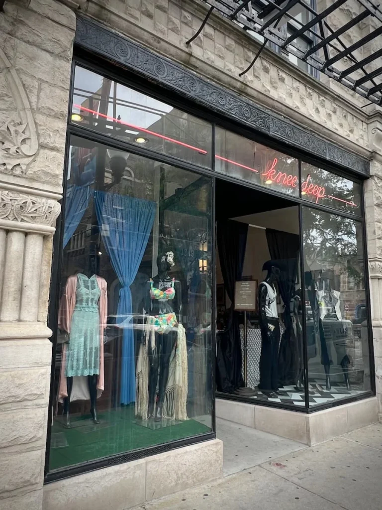 Exterior window display of pre-loved clothing in a double-faced window at Knee Deep Vintage, Chicago