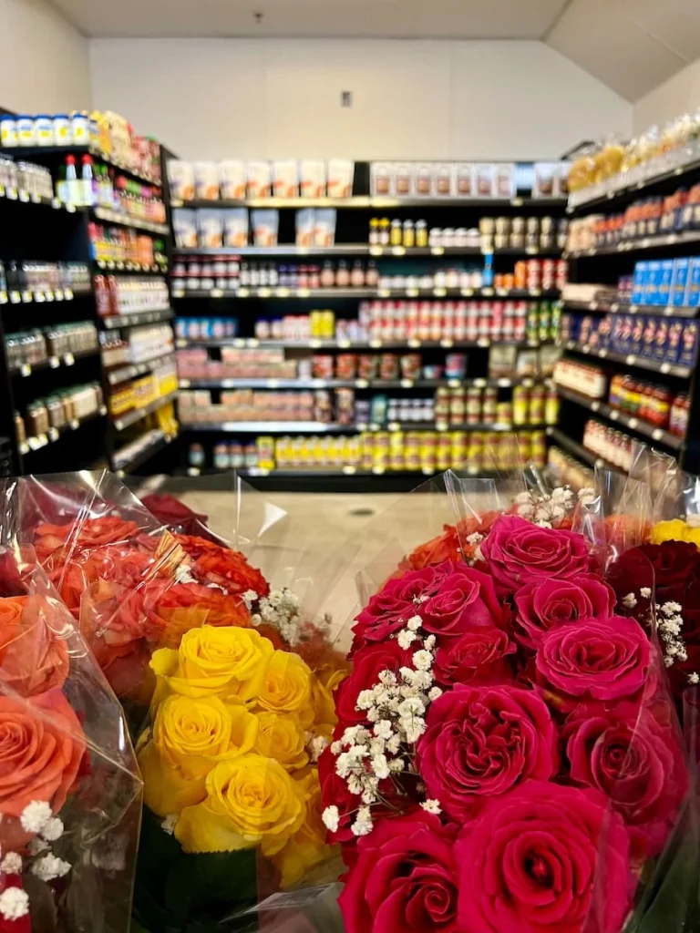 Flowers and groceries at The French Market in Chicago. Multicolour bunches on flowers with jars, cans and packets of local French and non-French produce lined up neatly on the shelves in the background