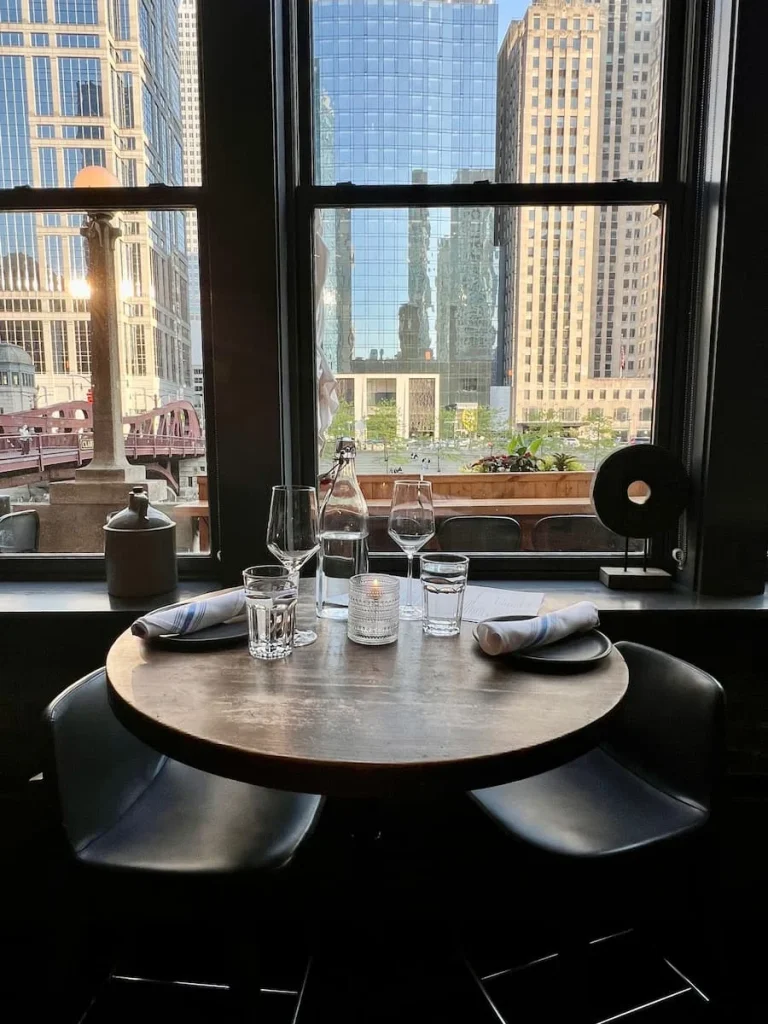 High table next to the window with 2 stools and view of the Chicago River at American Bistro, Chicago