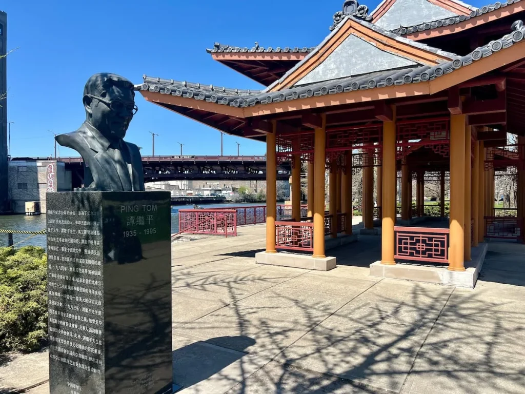Statue of Ping Tom next to the red Chinese Pergola in Ping Tom Memorial Park, Chicago
