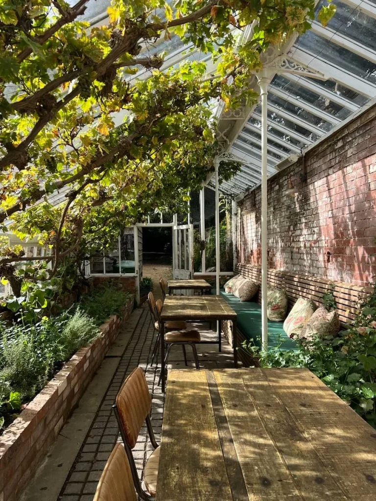 The greenhouse interior with cushioned seats and plants at Hampton Manor