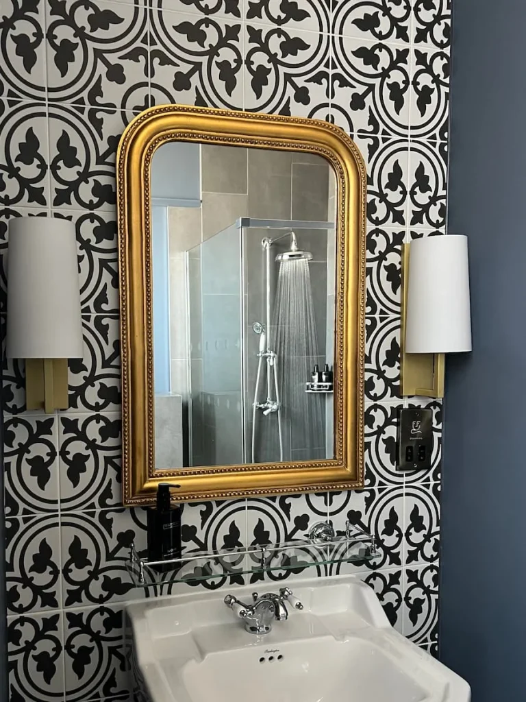 Vanity area with gold mirror and black and white tiles at St Martins Lodge, Leicester