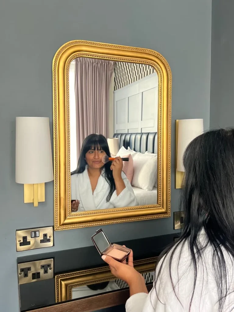 Bejal in mirror putting make-up on at St Martins Lodge, Leicester